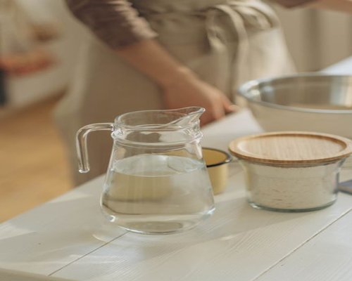 A clean, minimalist kitchen table prepared with a balanced homemade breakfast featuring fresh local ingredients and a pitcher of water